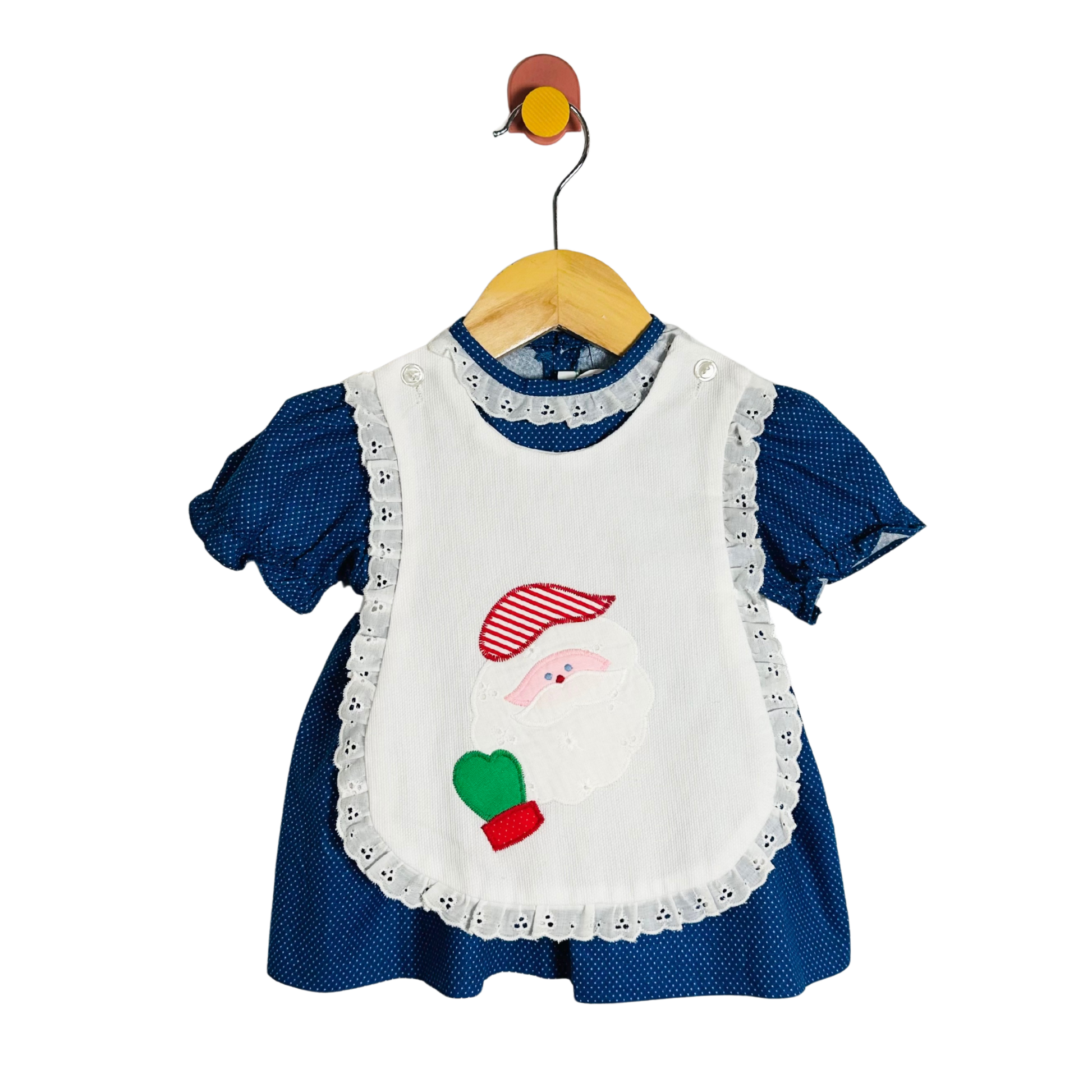 Blue dress with a white apron featuring a santa design on a hanger against a white background