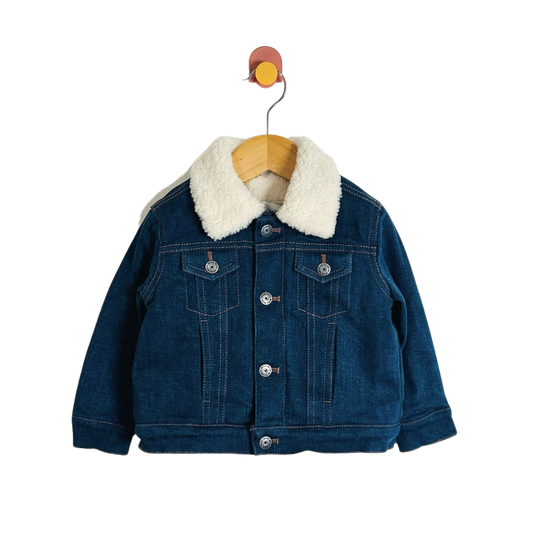 A children's dark blue denim jacket with a thick white sherpa fleece collar, hanging on a wooden hanger against a plain white background.