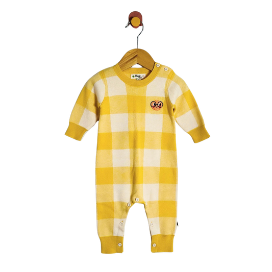A baby long-sleeve romper in a yellow and cream checkered gingham pattern, hanging on a wooden hanger against a plain white background. The romper features a small cartoon patch on the left chest and snap closures at the crotch and shoulders.