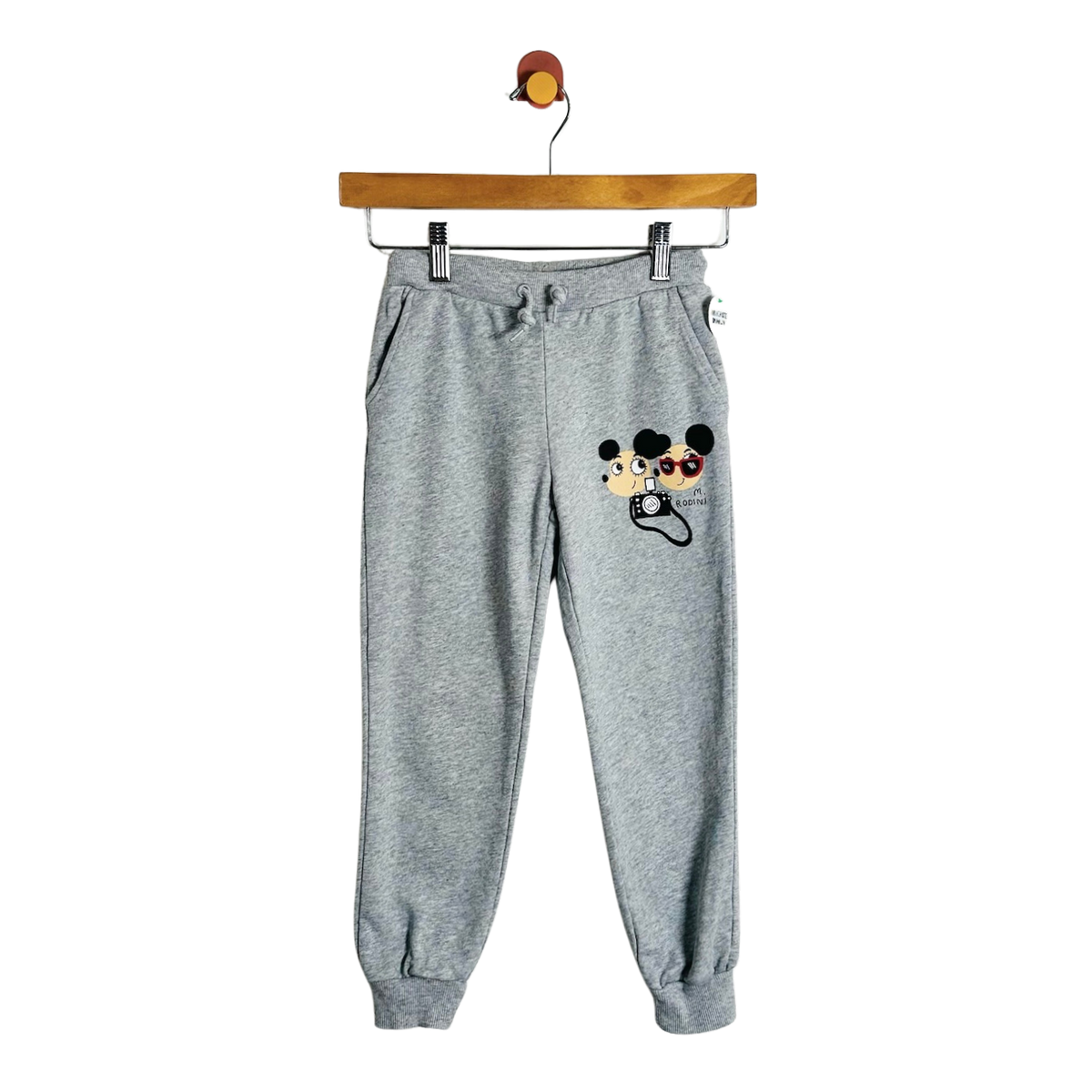 Gray heather jogger sweatpants with a Mickey Mouse and Minnie Mouse graphic on the left thigh, hanging from a wooden hanger against a white background.