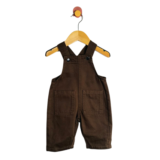 A baby romper in dark brown corduroy fabric, hanging on a wooden hanger against a solid white background.