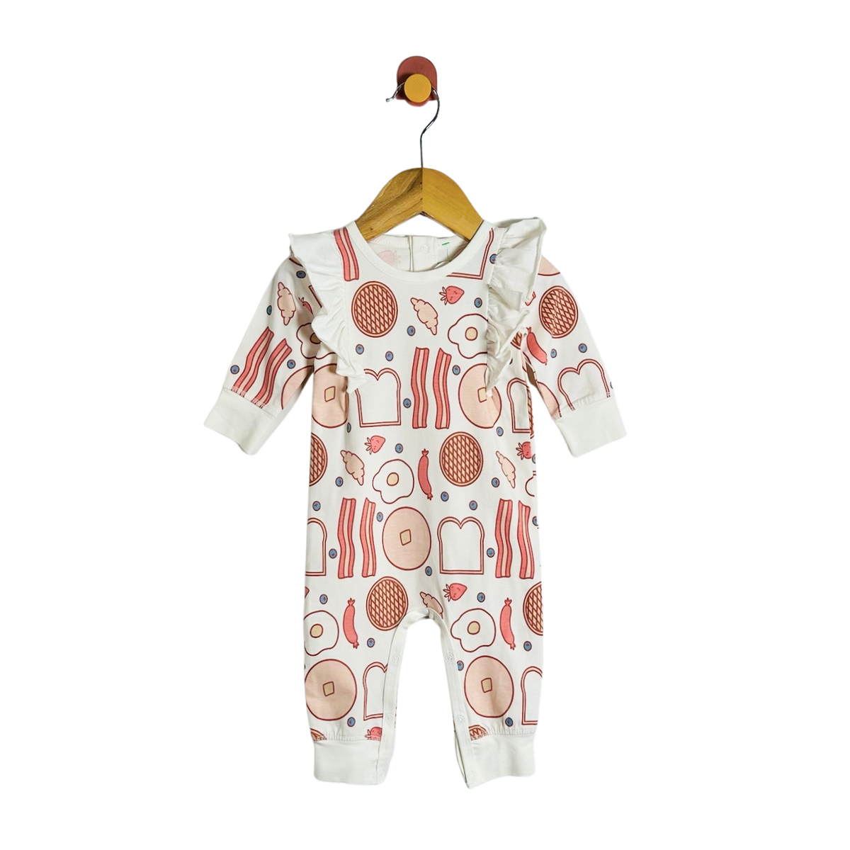 A baby long-sleeve footless romper hanging on a wooden hanger against a plain white background. The romper is off-white with a colorful breakfast food print featuring eggs, bacon, toast, and pancakes.