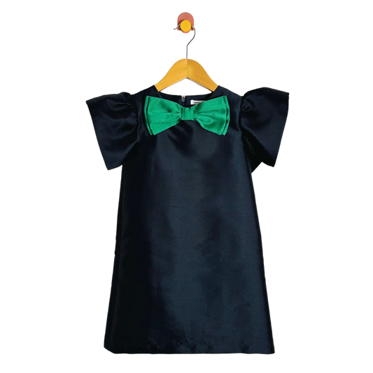 Blue dress with green bow on a hanger against a white background