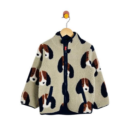 A children's sherpa zip-up fleece jacket with an all-over dog face print, hanging on a wooden hanger against a plain white background.