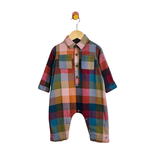A baby romper with a colorful plaid pattern, featuring a button-down shirt collar and three-quarter sleeves, hanging on a wooden hanger against a white background.