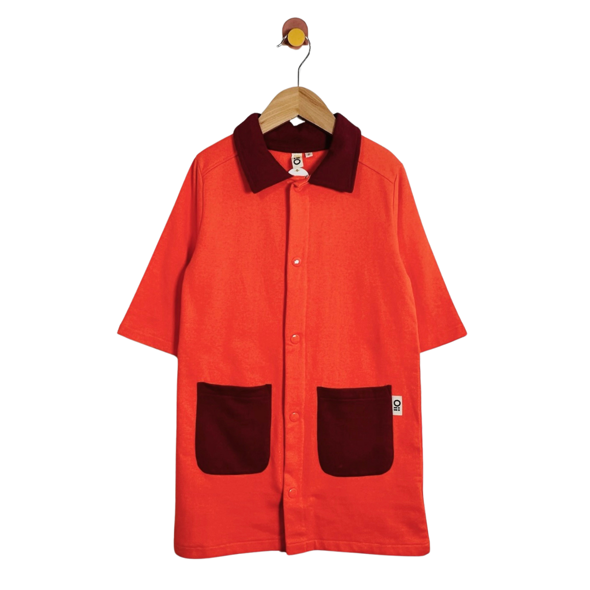 A short-sleeve button-front overshirt in bright orange corduroy with contrasting dark burgundy corduroy collar and pockets, hanging on a wooden hanger against a plain white background.