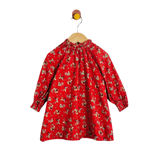 A red long-sleeve blouse with a dense small print, hanging on a wooden hanger against a plain white background.