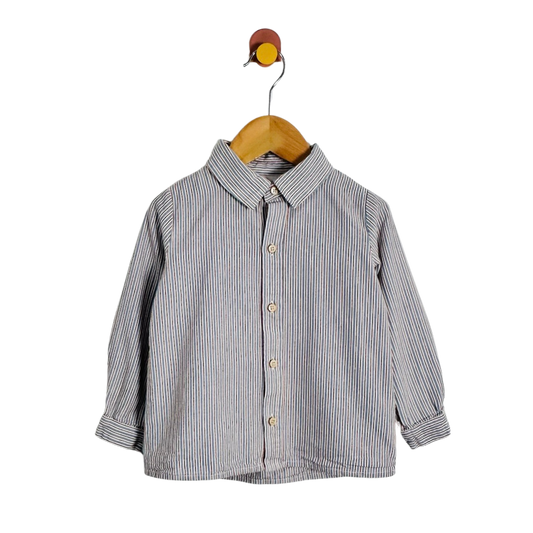 A toddler's long-sleeve button-down shirt with vertical blue and white stripes, hanging on a wooden hanger against a plain white background.