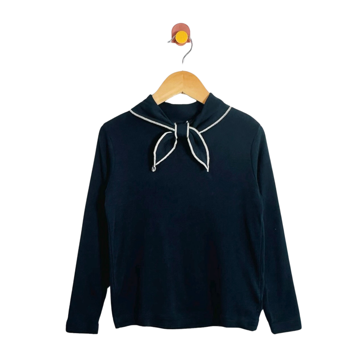 A dark navy long-sleeve top with a white-trimmed sailor-style collar and bow detail, hanging on a wooden hanger against a plain white background.