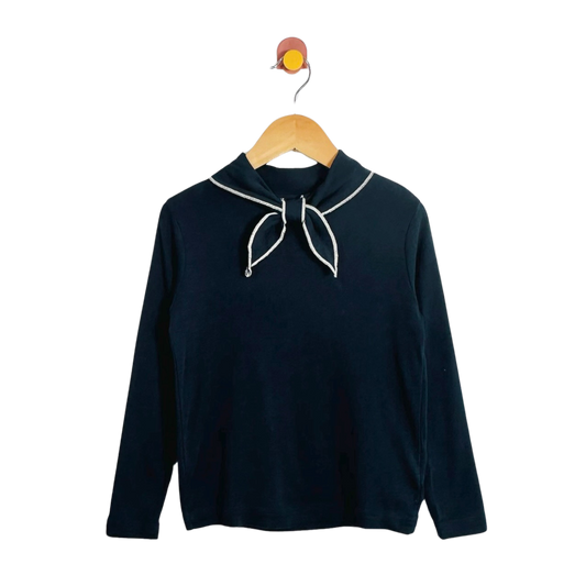 A dark navy long-sleeve top with a white-trimmed sailor-style collar and bow detail, hanging on a wooden hanger against a plain white background.