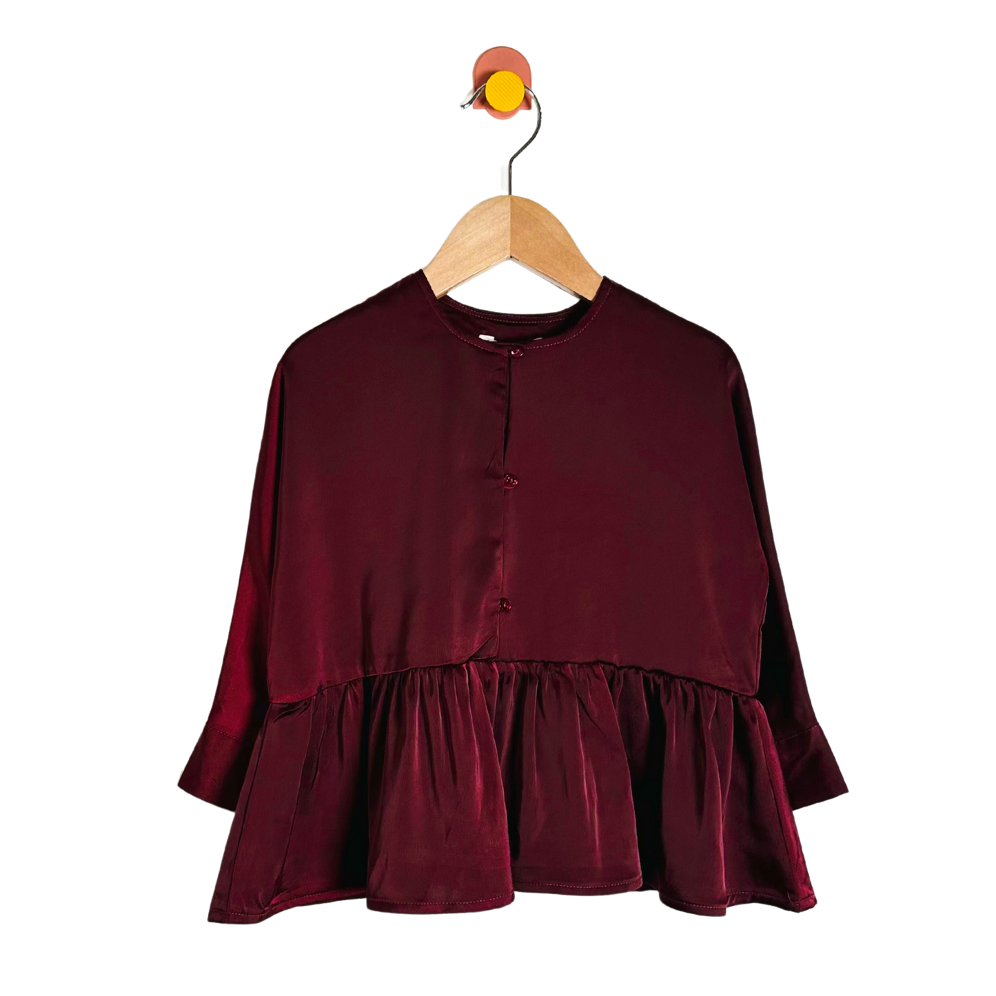 Maroon blouse with ruffled layers on a wooden hanger against a white background