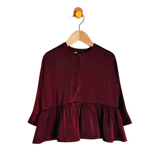 Maroon blouse with ruffled layers on a wooden hanger against a white background