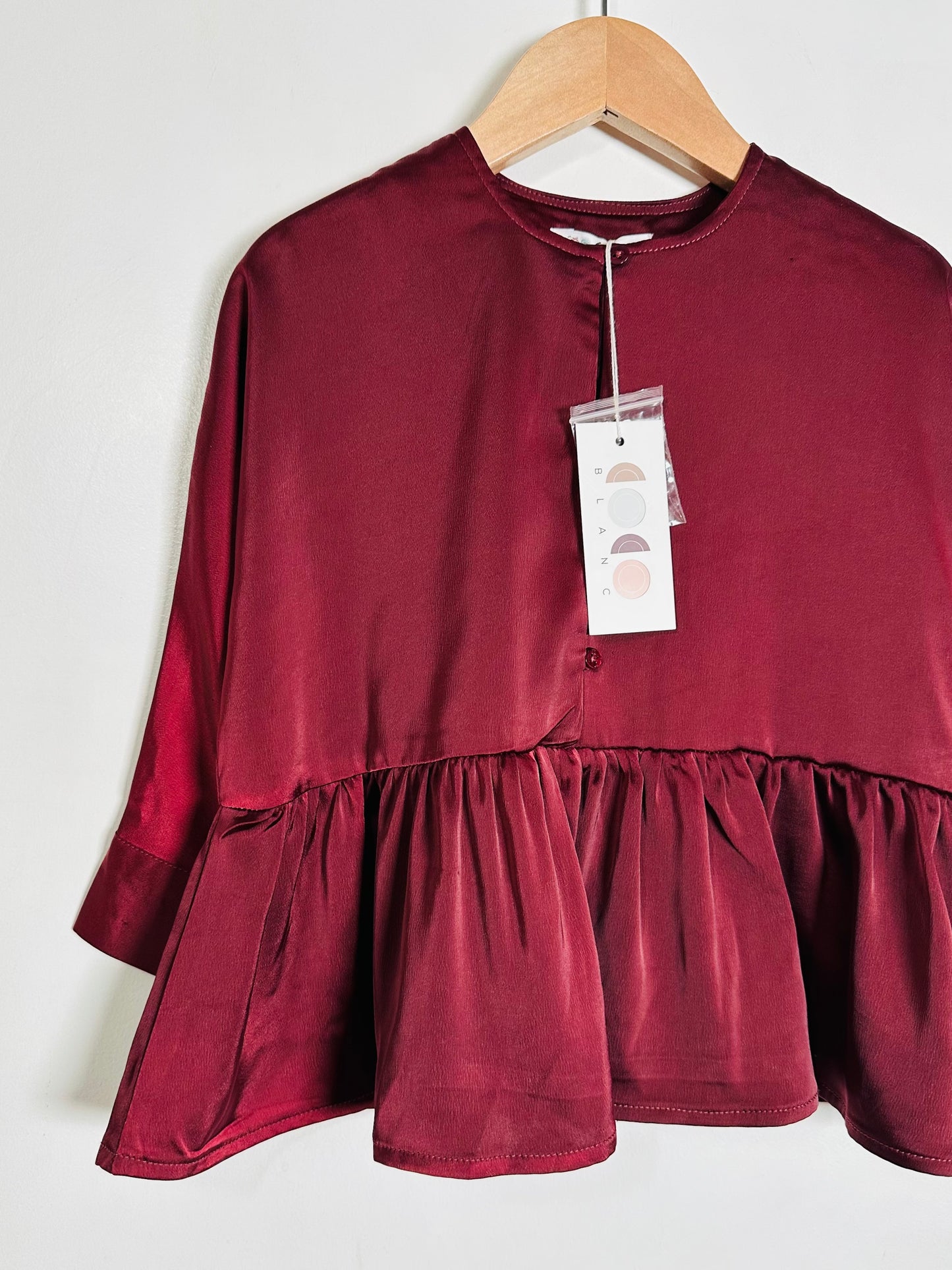 Maroon blouse on a hanger with a white background