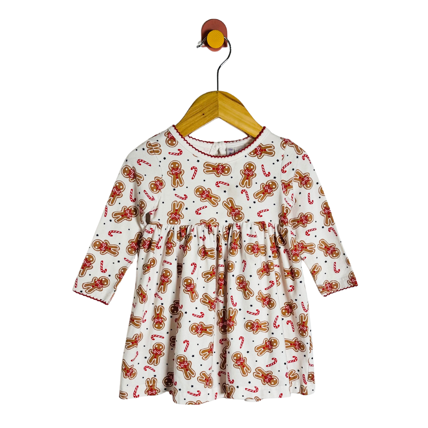 Children's dress with gingerbread pattern on a hanger against a white background