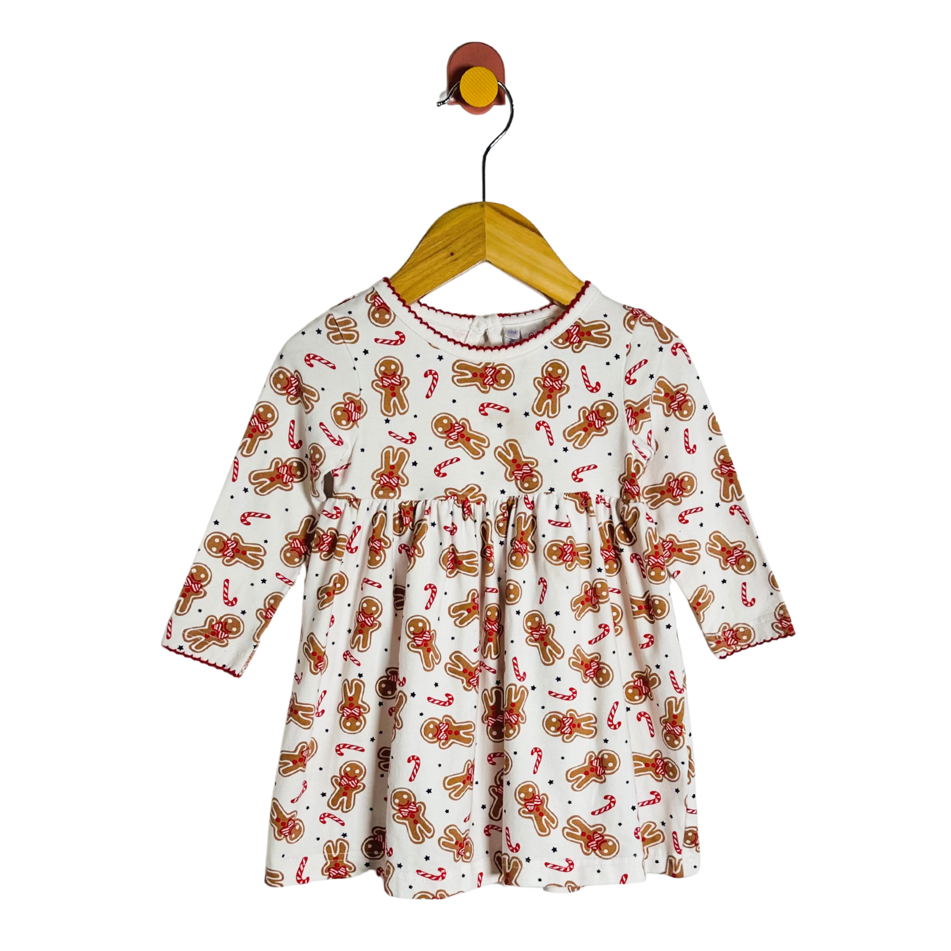 Children's dress with gingerbread pattern on a hanger against a white background