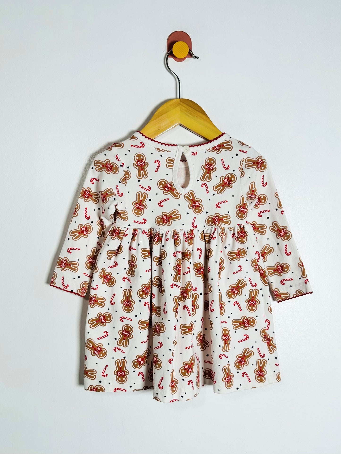 Children's dress with gingerbread pattern on a hanger against a white background