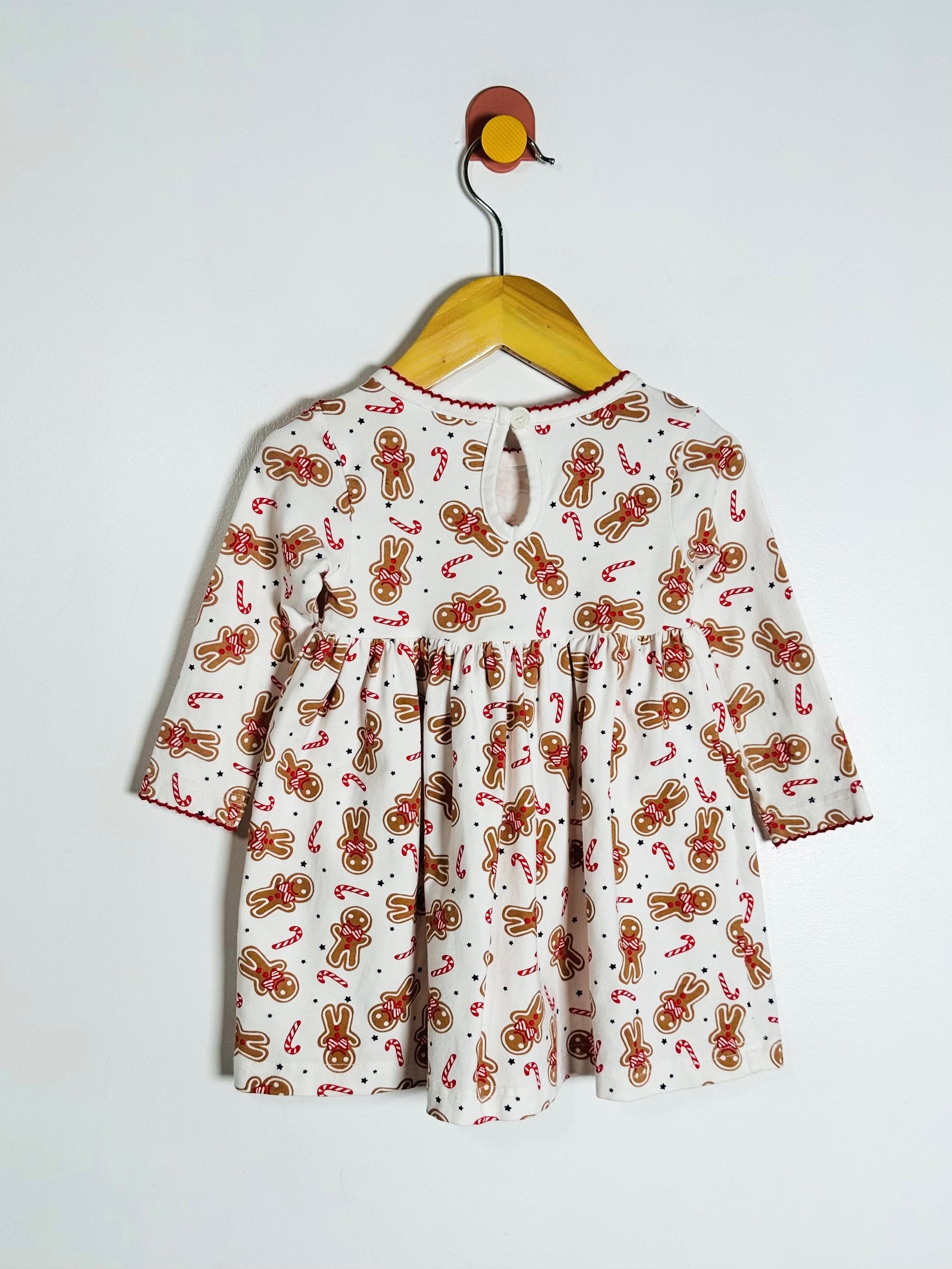 Children's dress with gingerbread pattern on a hanger against a white background