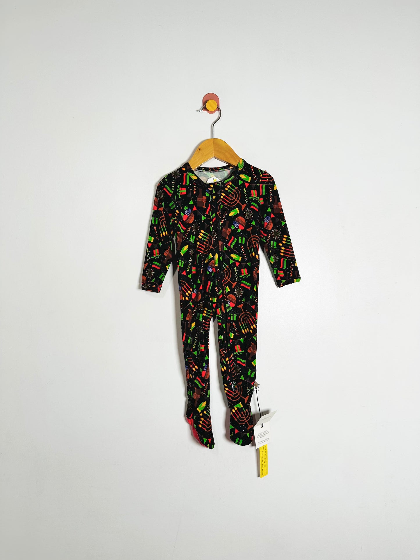 Children's onesie with colorful pattern on a hanger against a white background