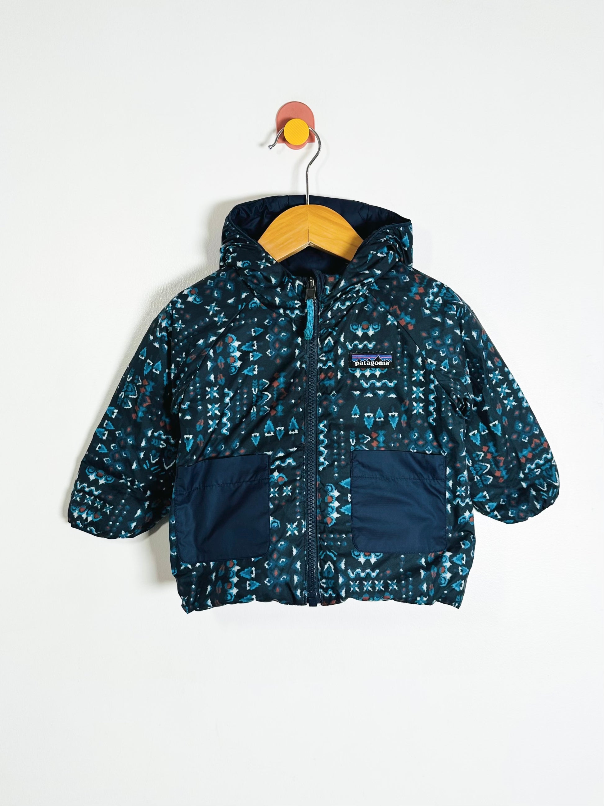 Navy patterned jacket on a hanger against a white background