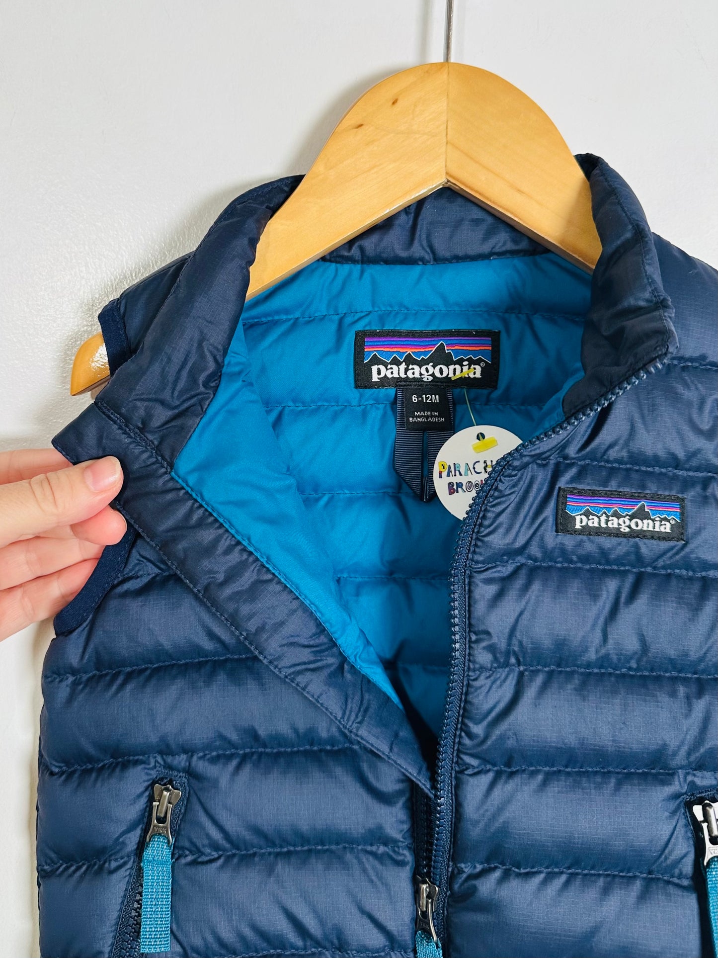 Blue puffer vest with Patagonia logo on a hanger against a white background