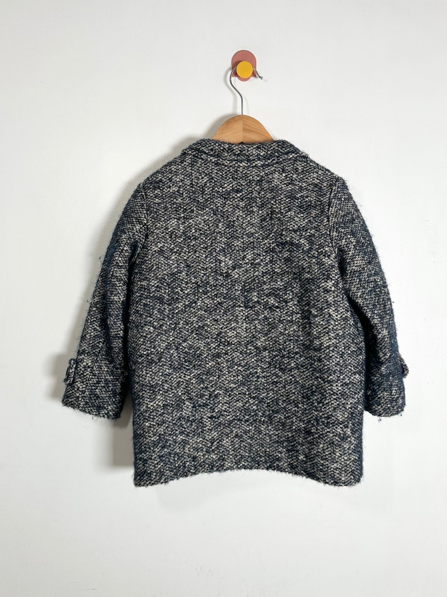 Black and white patterned coat on a hanger against a white background