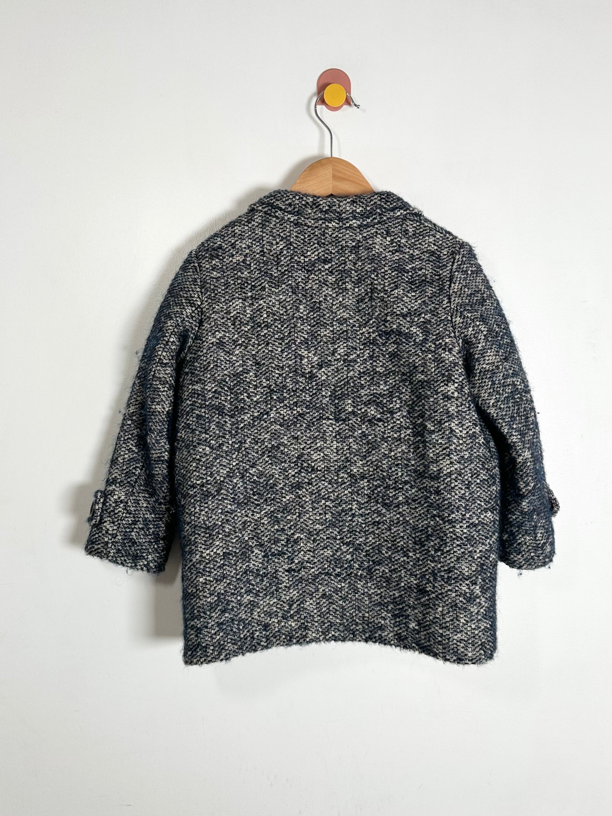 Black and white patterned coat on a hanger against a white background