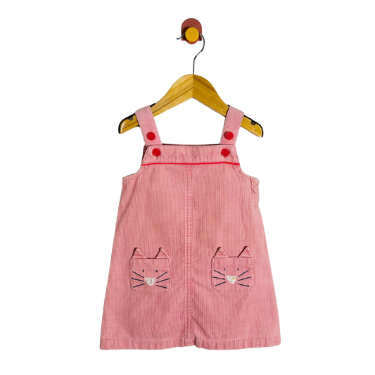 Pink children's dress with cat face pockets on a hanger against a white background