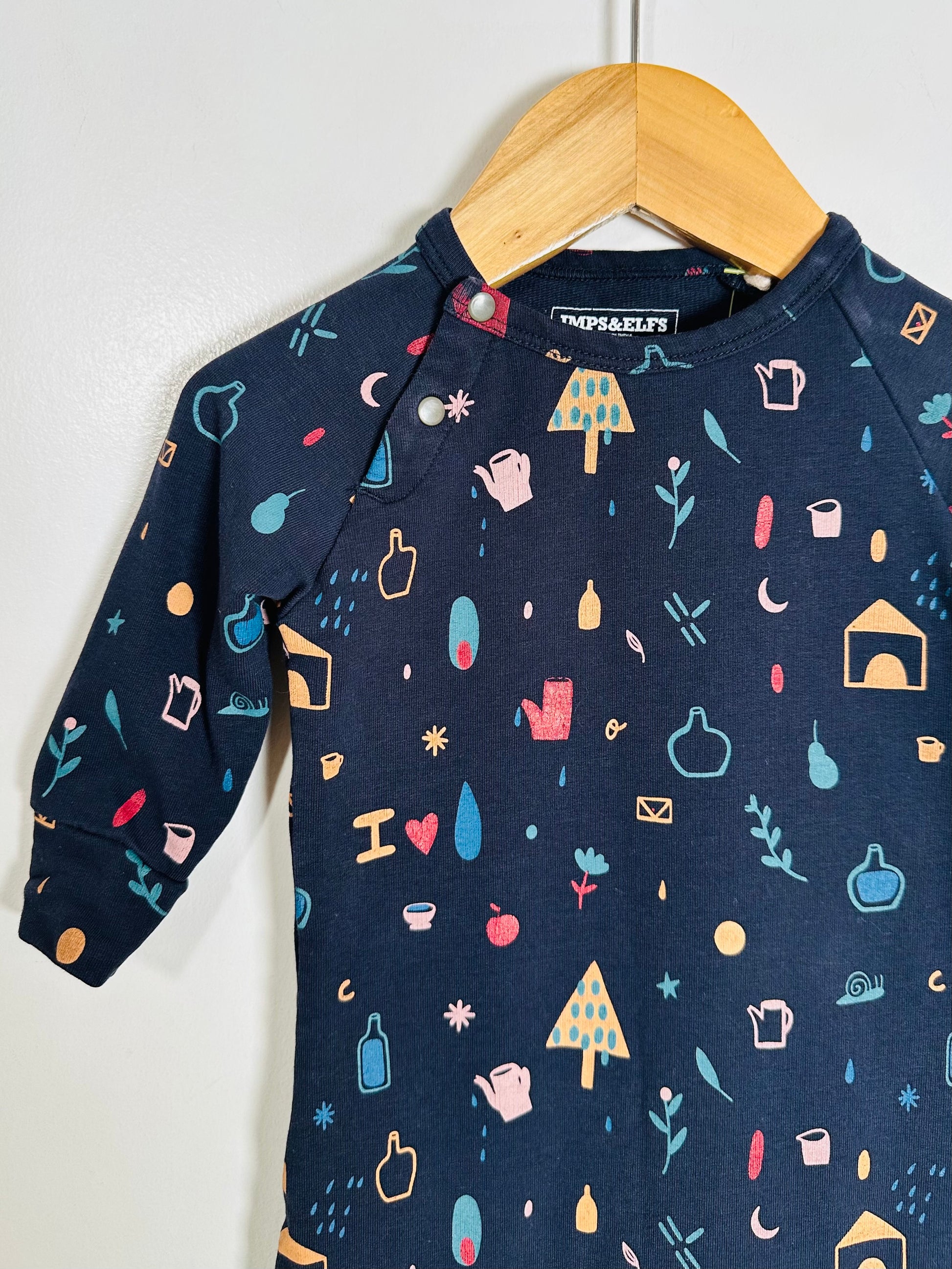 Navy blue children's shirt with colorful pattern on a wooden hanger against a white background