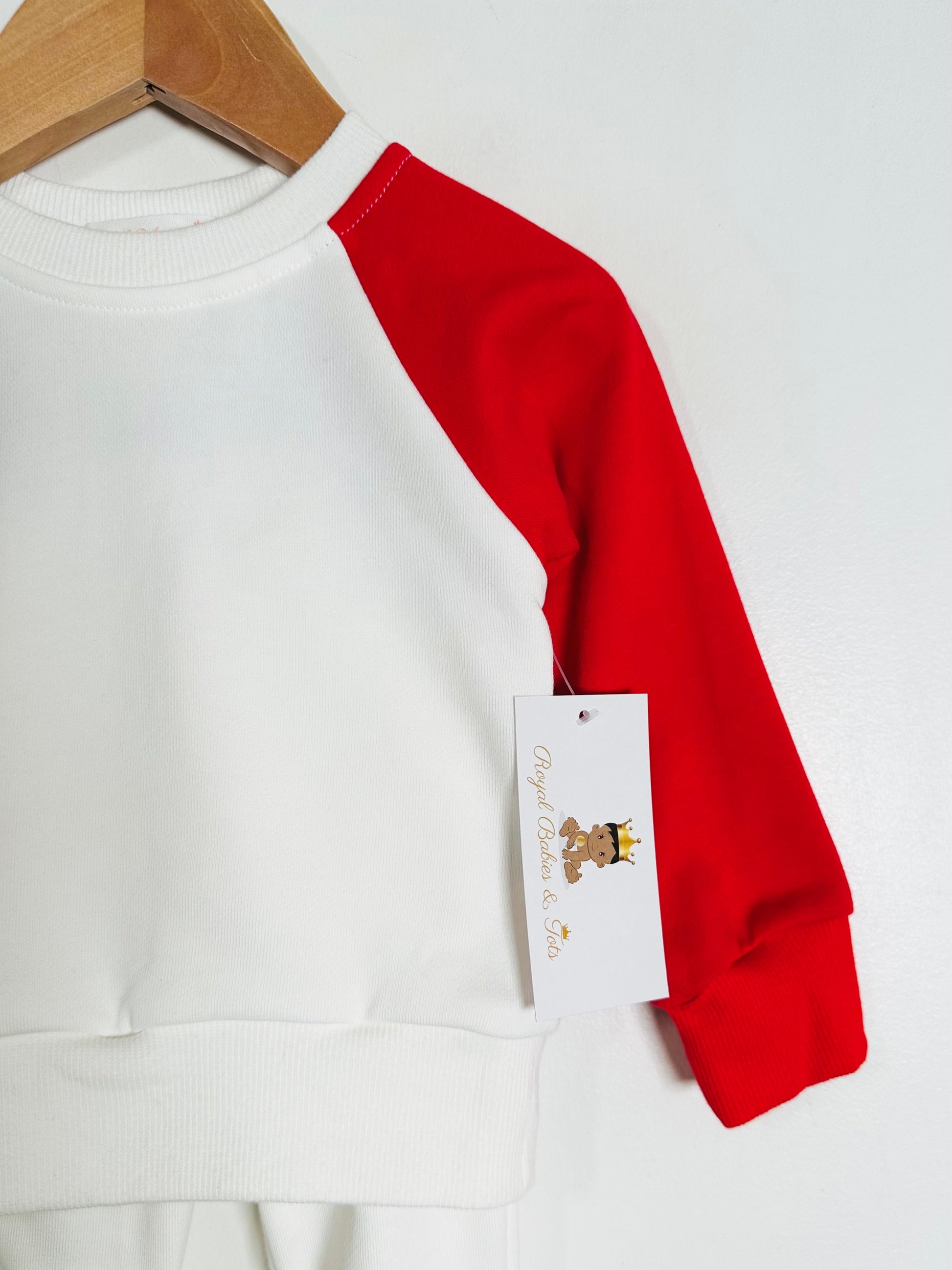 White sweatshirt with red sleeves on a hanger against a white background
