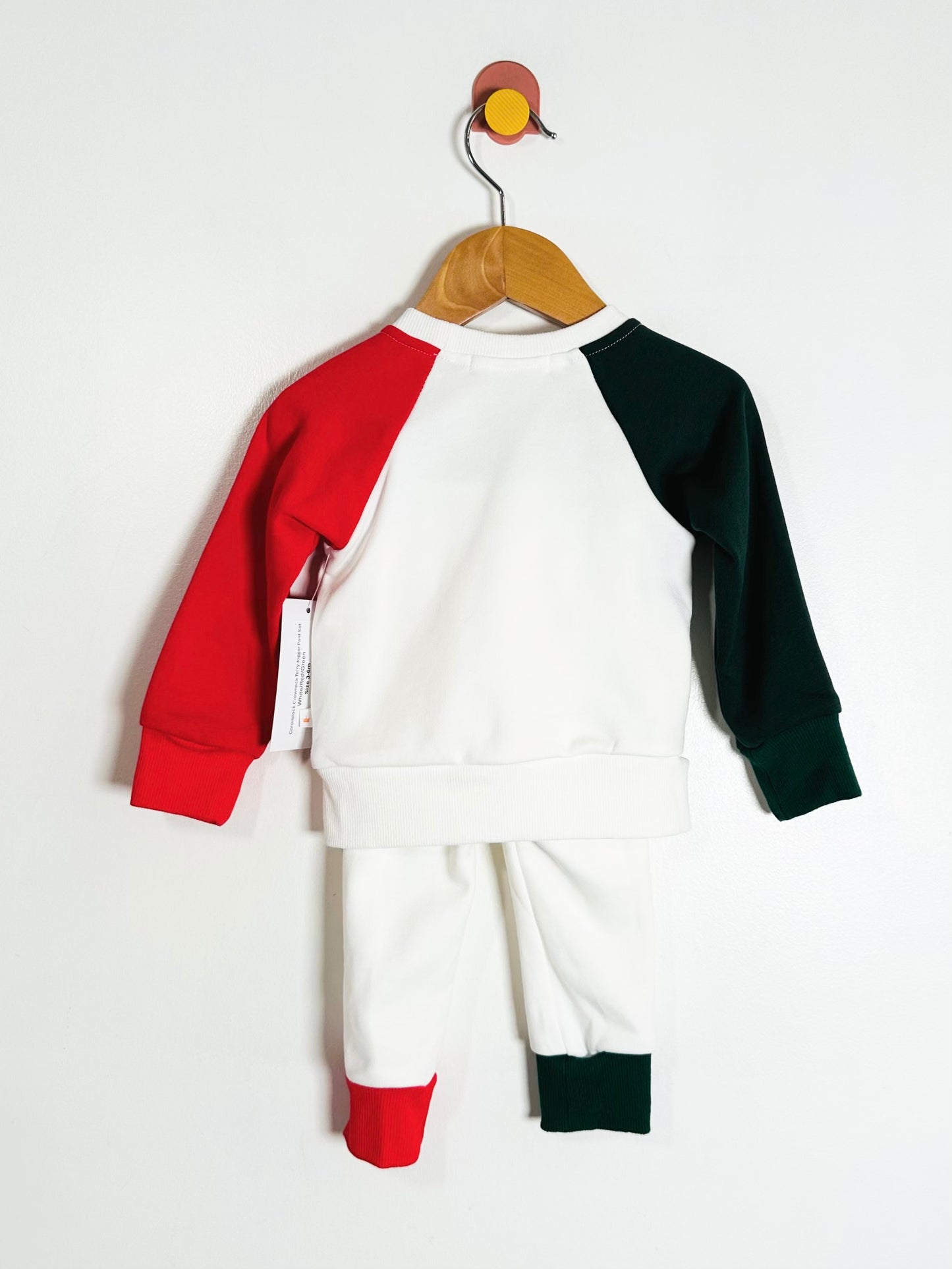 Children's outfit with red, white, and green long-sleeve top and pants on a hanger against a white background.