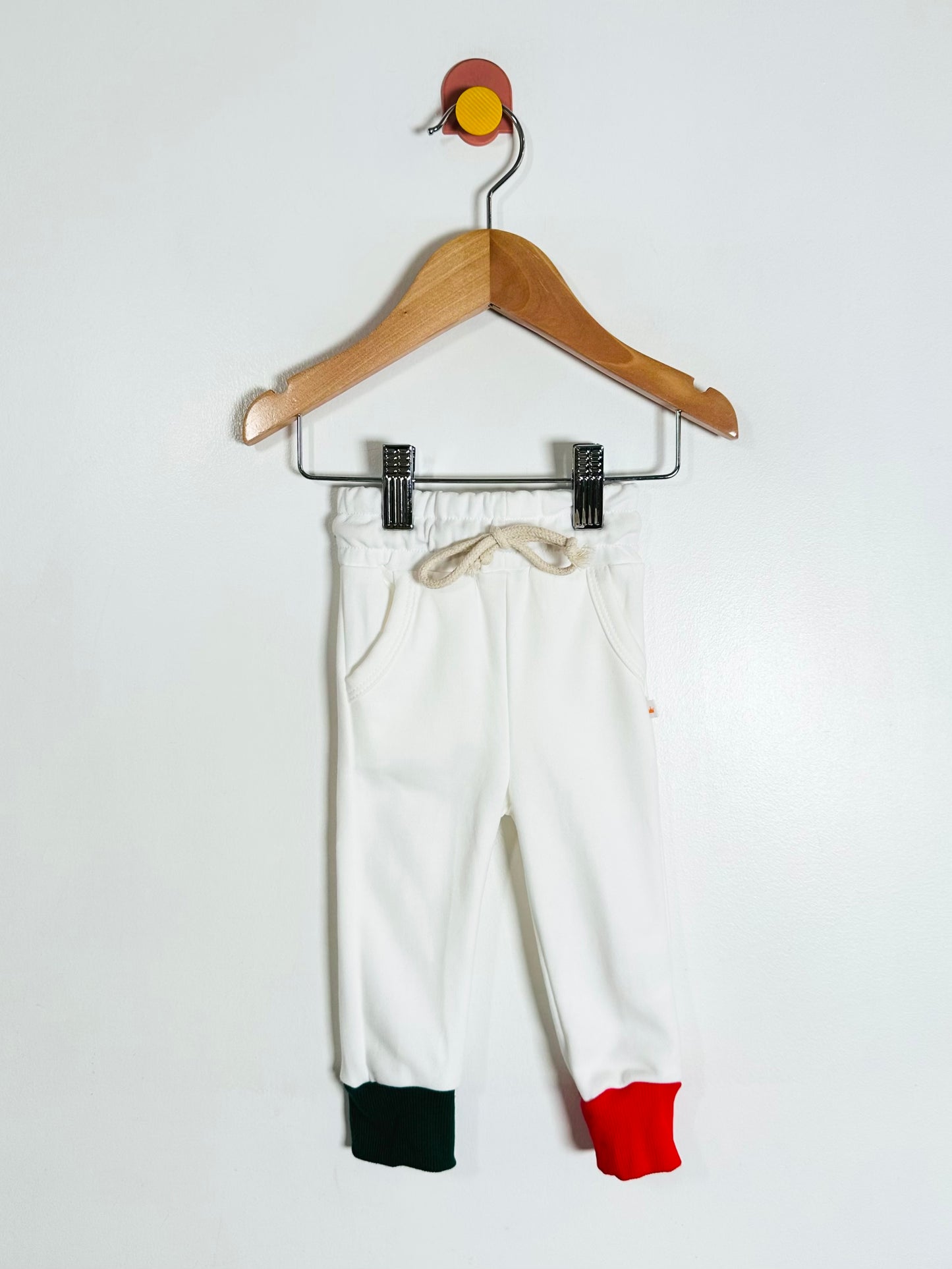 White pants with red and green accents on a hanger against a white background