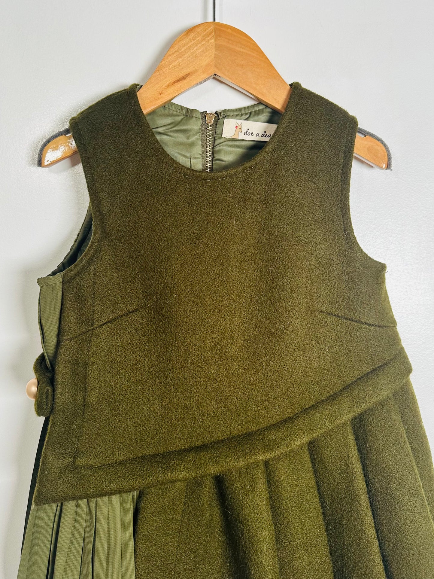Green dress on a wooden hanger against a white background