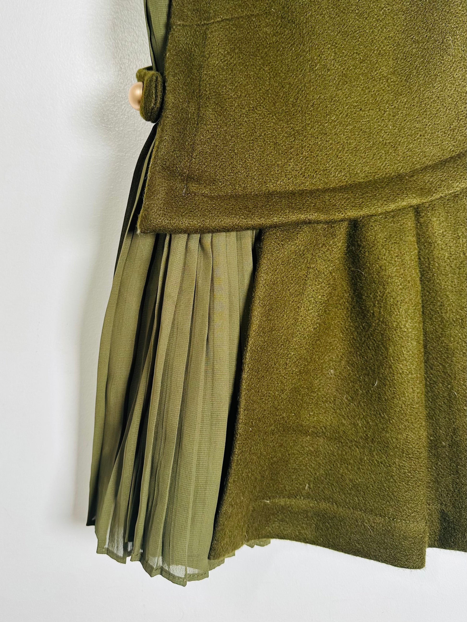 Green pleated skirt with a button detail on a white background