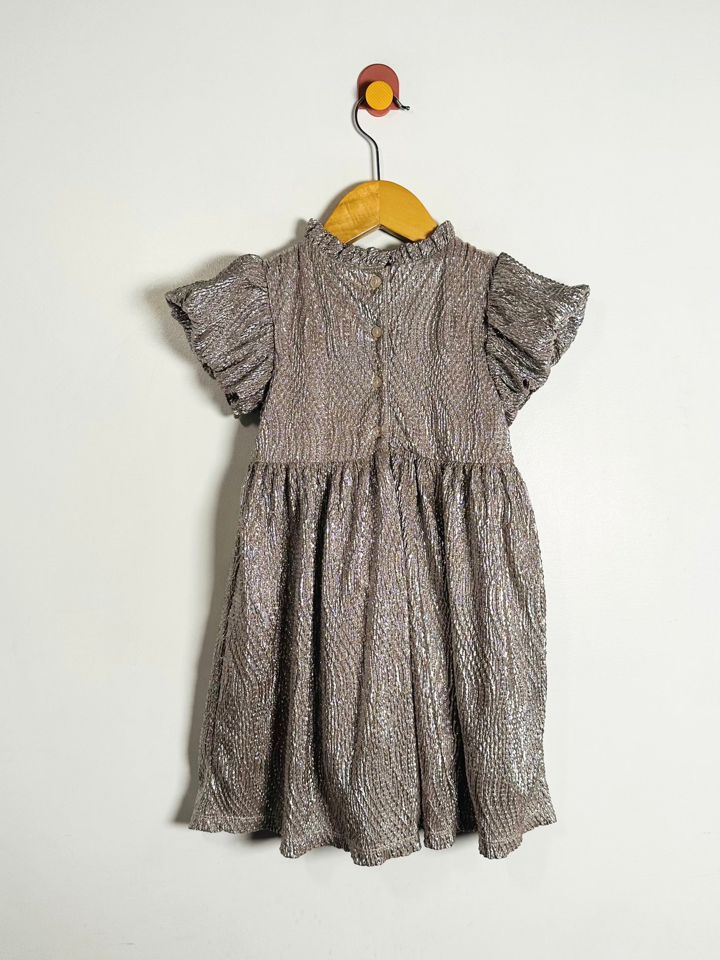 Children's dress with ruffled sleeves on a hanger against a white background