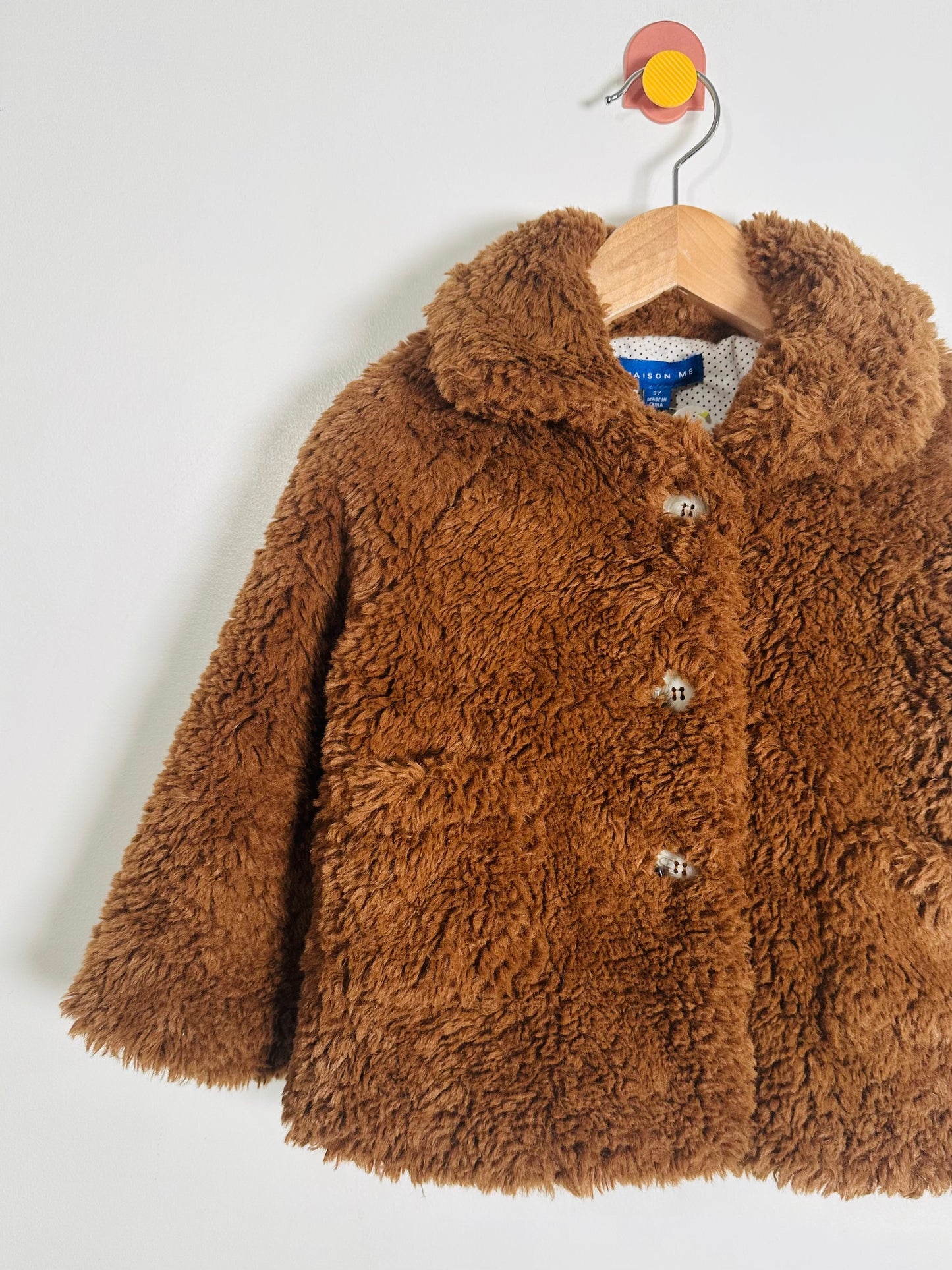 Brown fluffy coat on a hanger against a white background