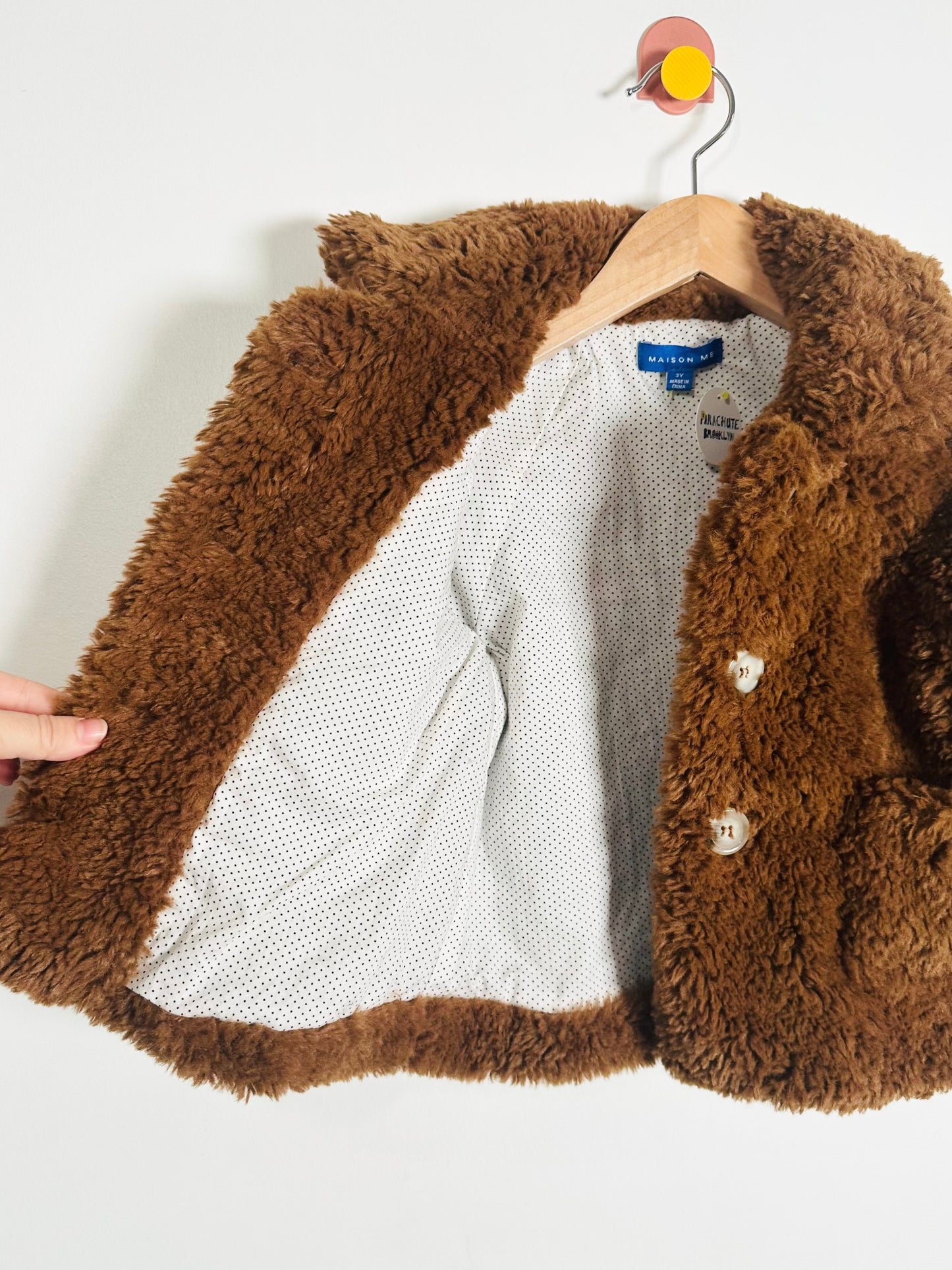 Brown fluffy jacket on a hanger with a white background