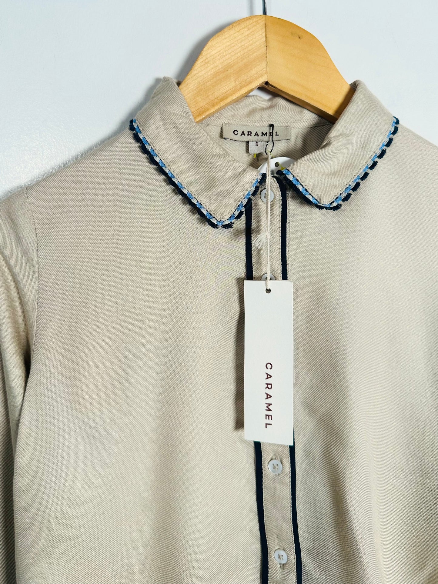 Beige shirt with decorative collar on a hanger, featuring a Caramel label.