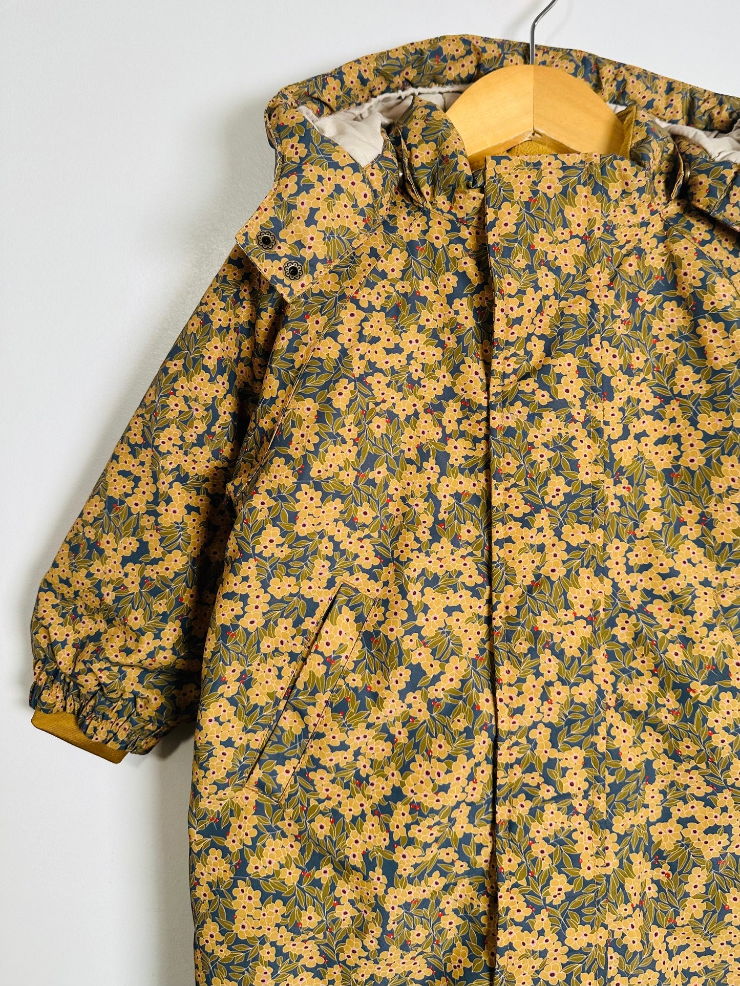 Floral-patterned snowsuit on a hanger against a white background