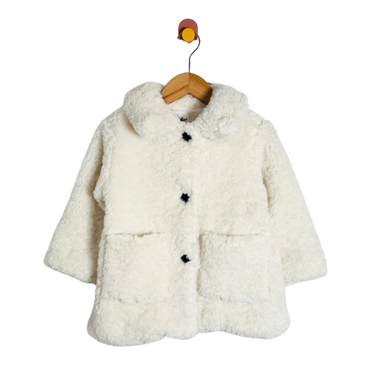 White fluffy coat on a wooden hanger against a white background
