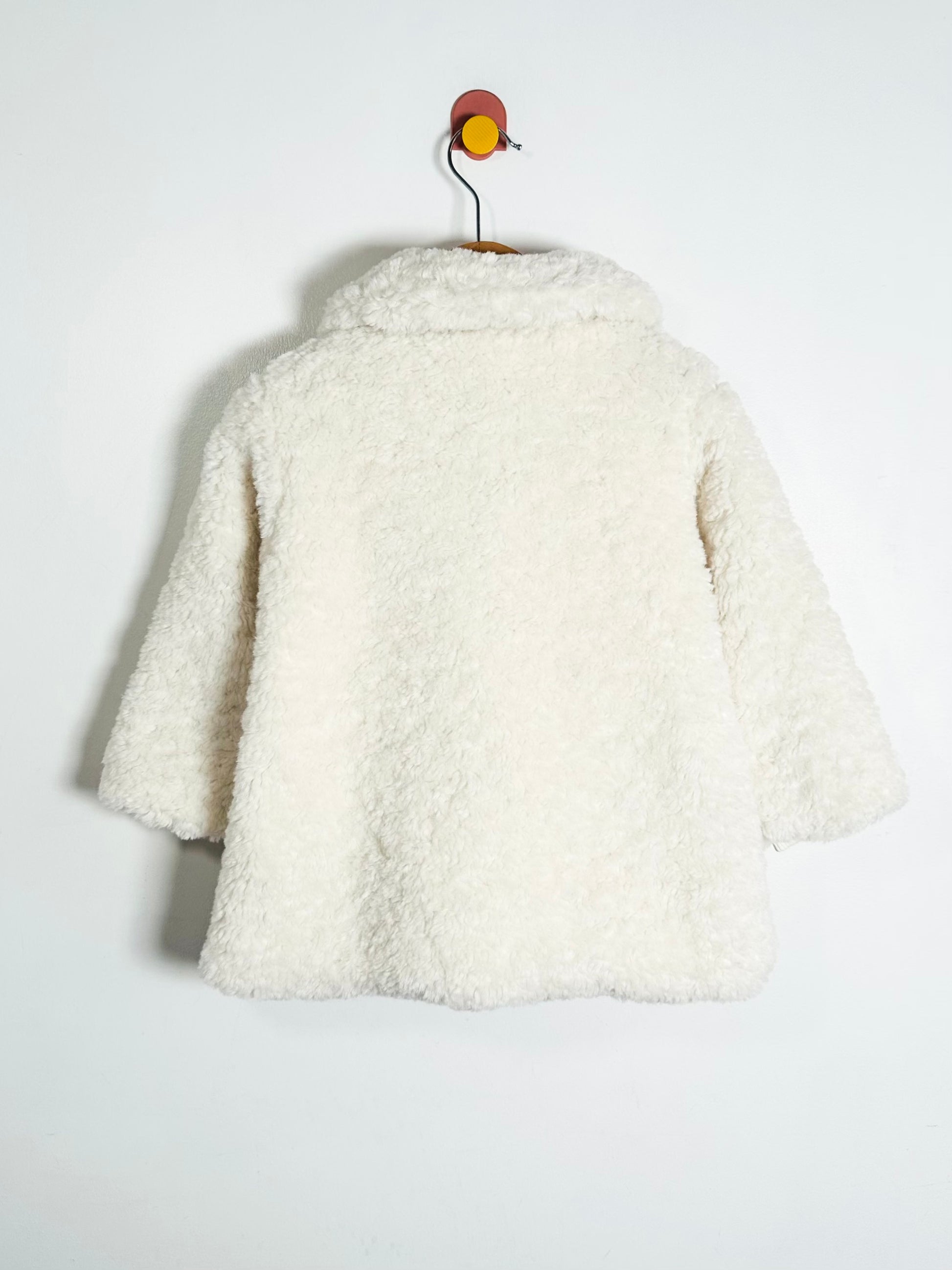 White textured jacket on a hanger against a white background