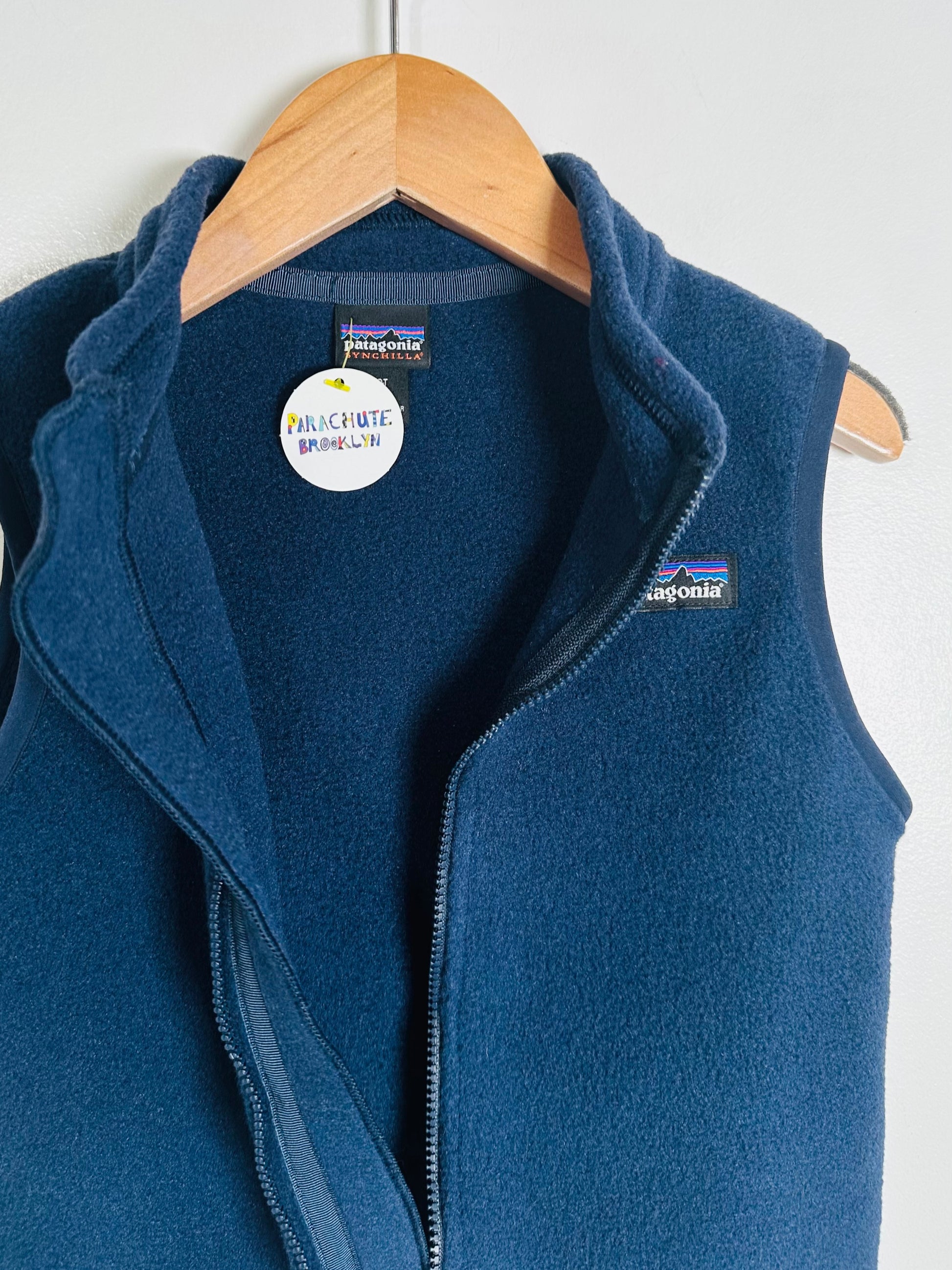 Blue fleece vest on a wooden hanger with Patagonia branding.