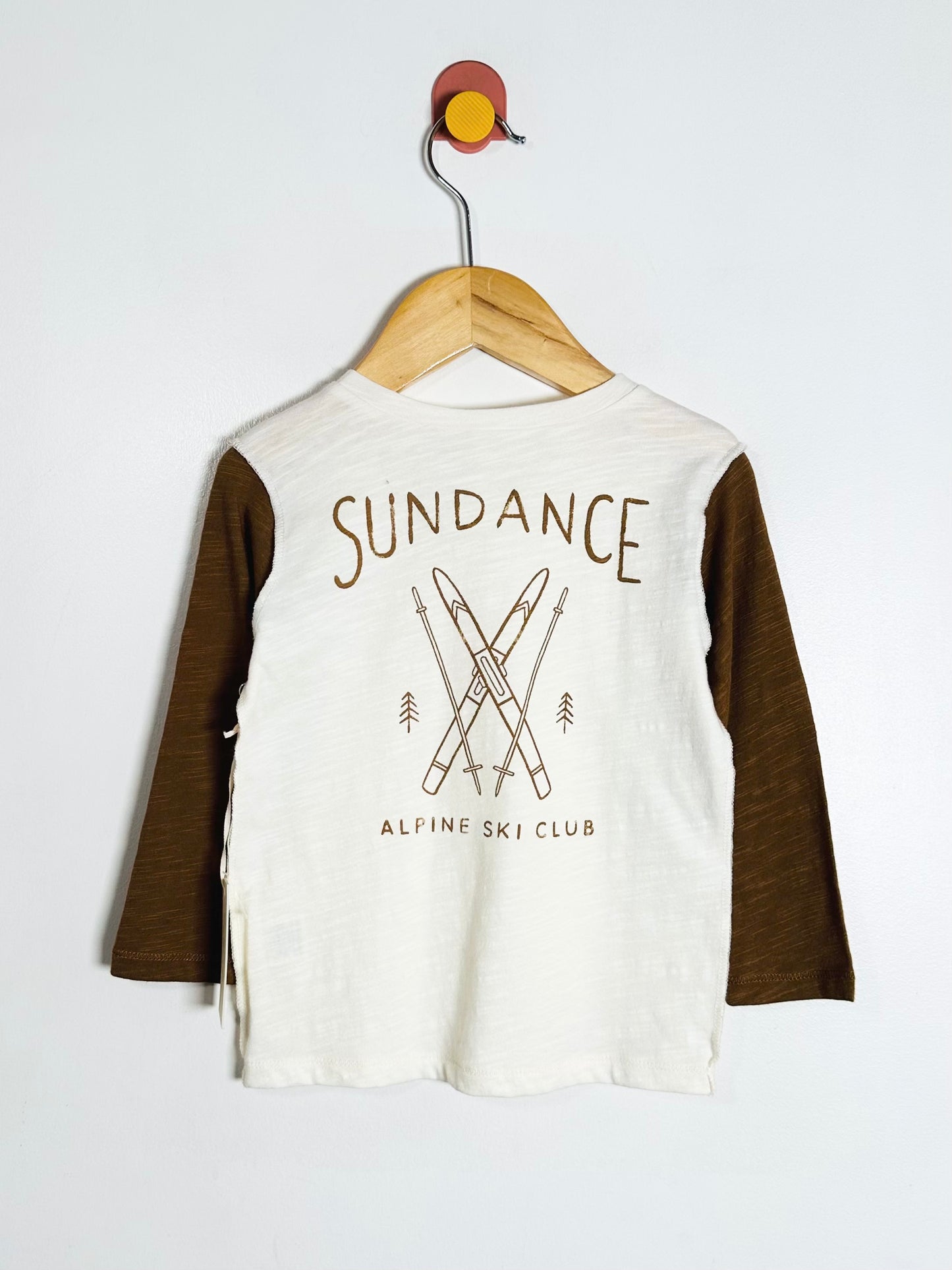 Children's long-sleeve shirt with 'Sundance Alpine Ski Club' design on a hanger against a white background