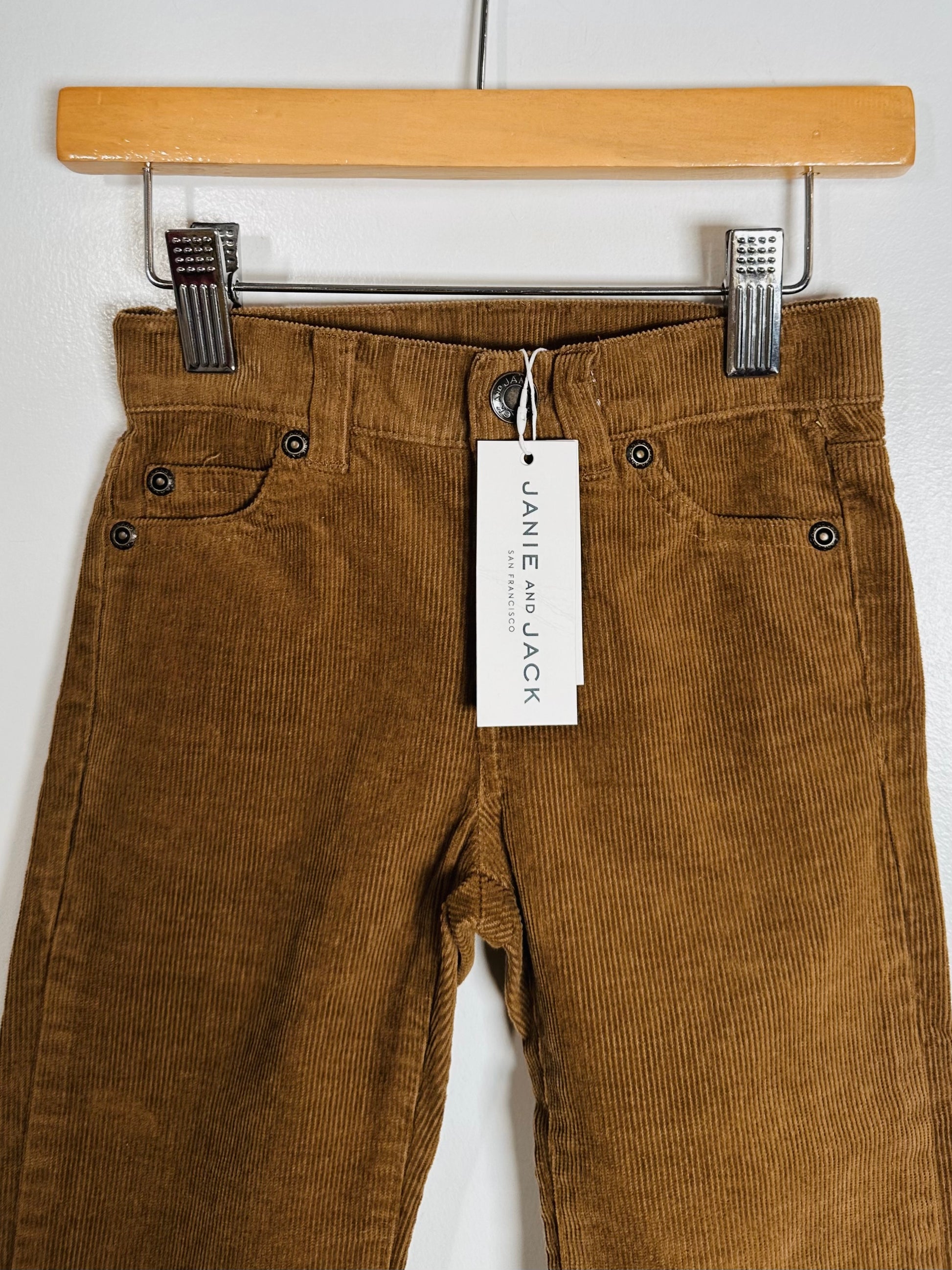 Brown corduroy pants on a hanger with a Janie and Jack tag.