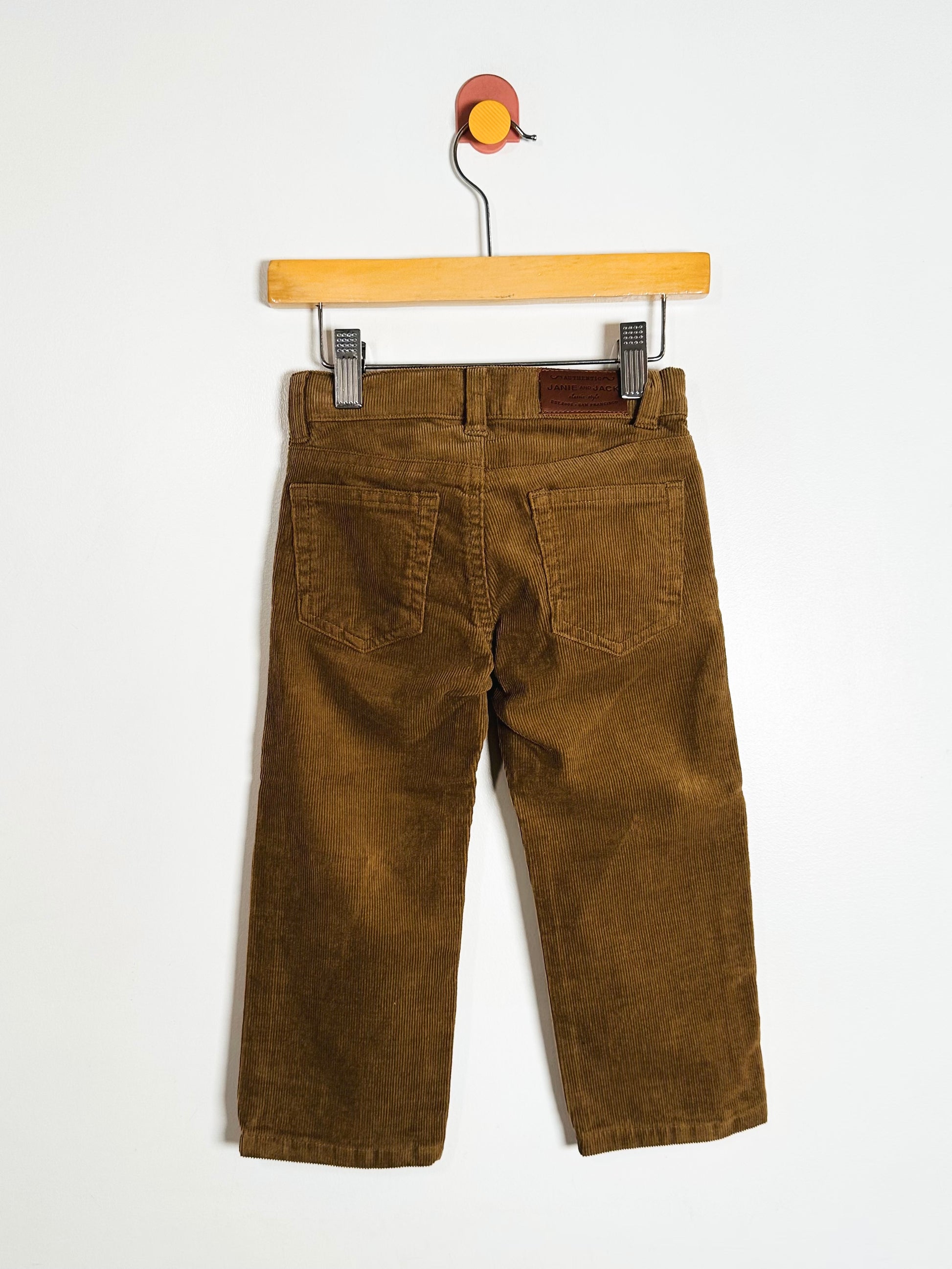 Brown pants on a wooden hanger against a white background