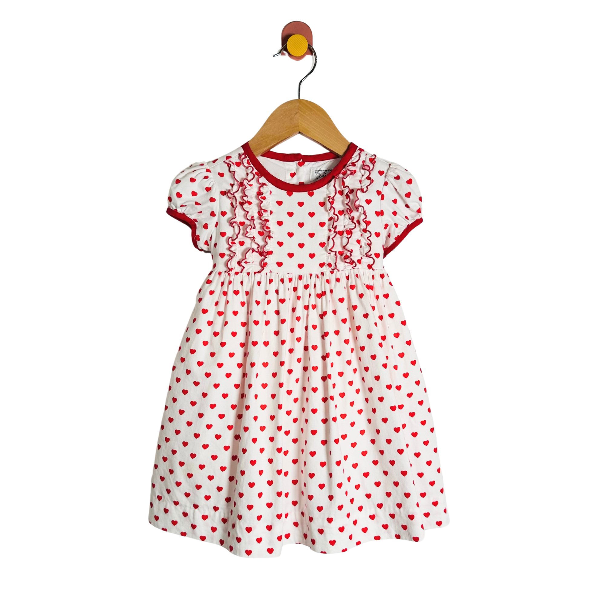 White dress with red heart patterns on a hanger against a white background