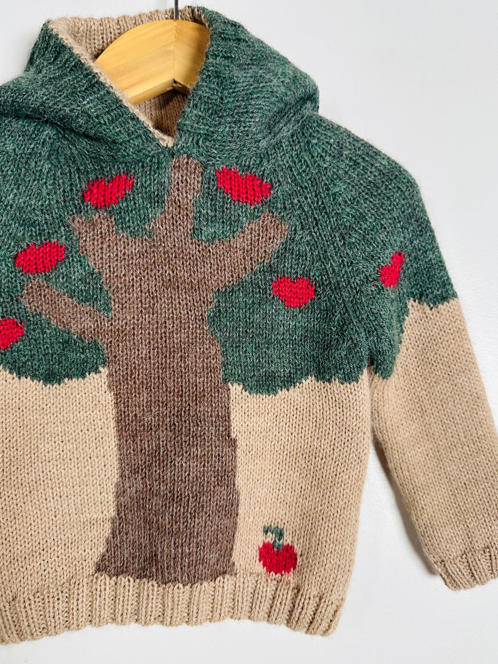 Knitted sweater with tree and apple design on a white background