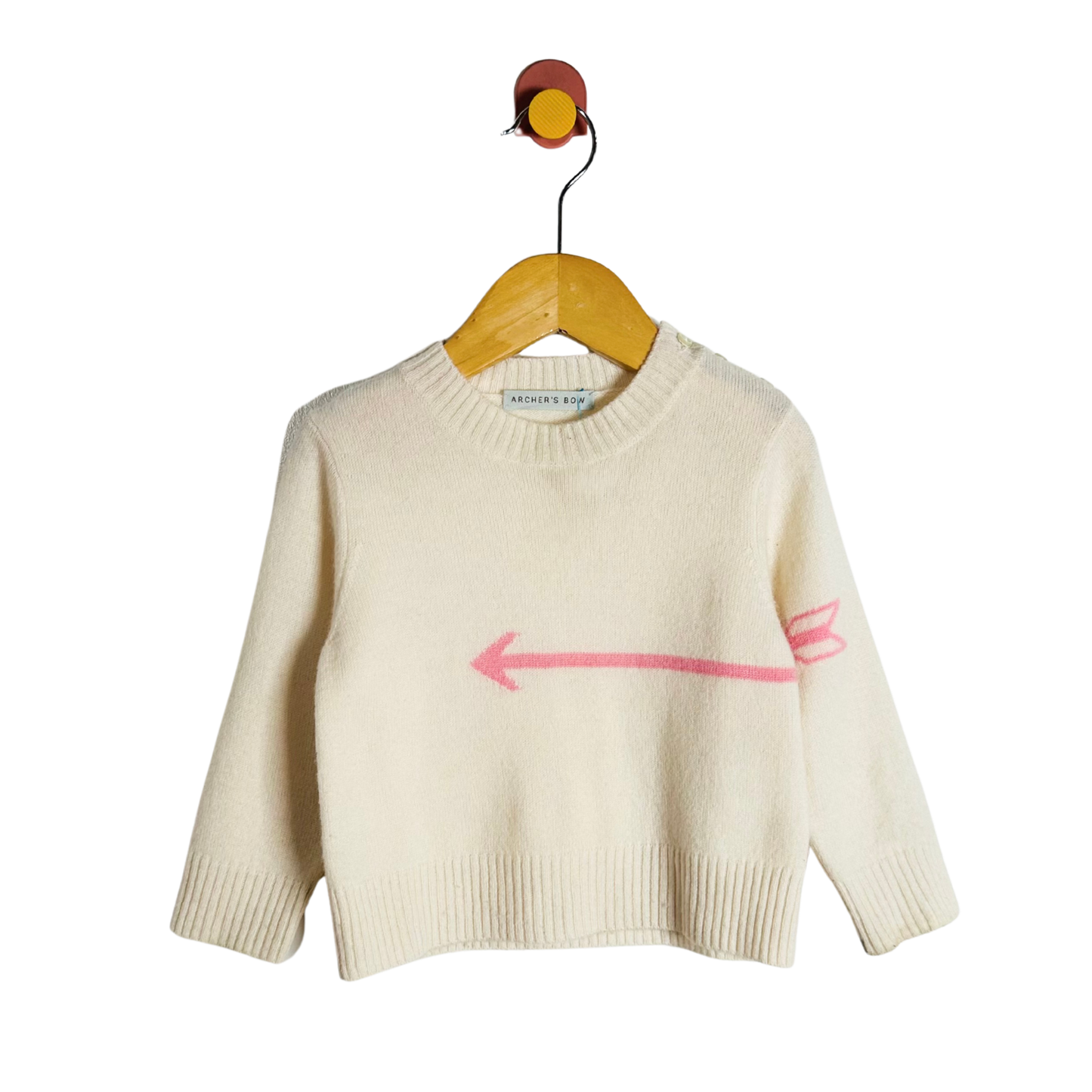 Beige sweater with a pink arrow design on a hanger against a white background