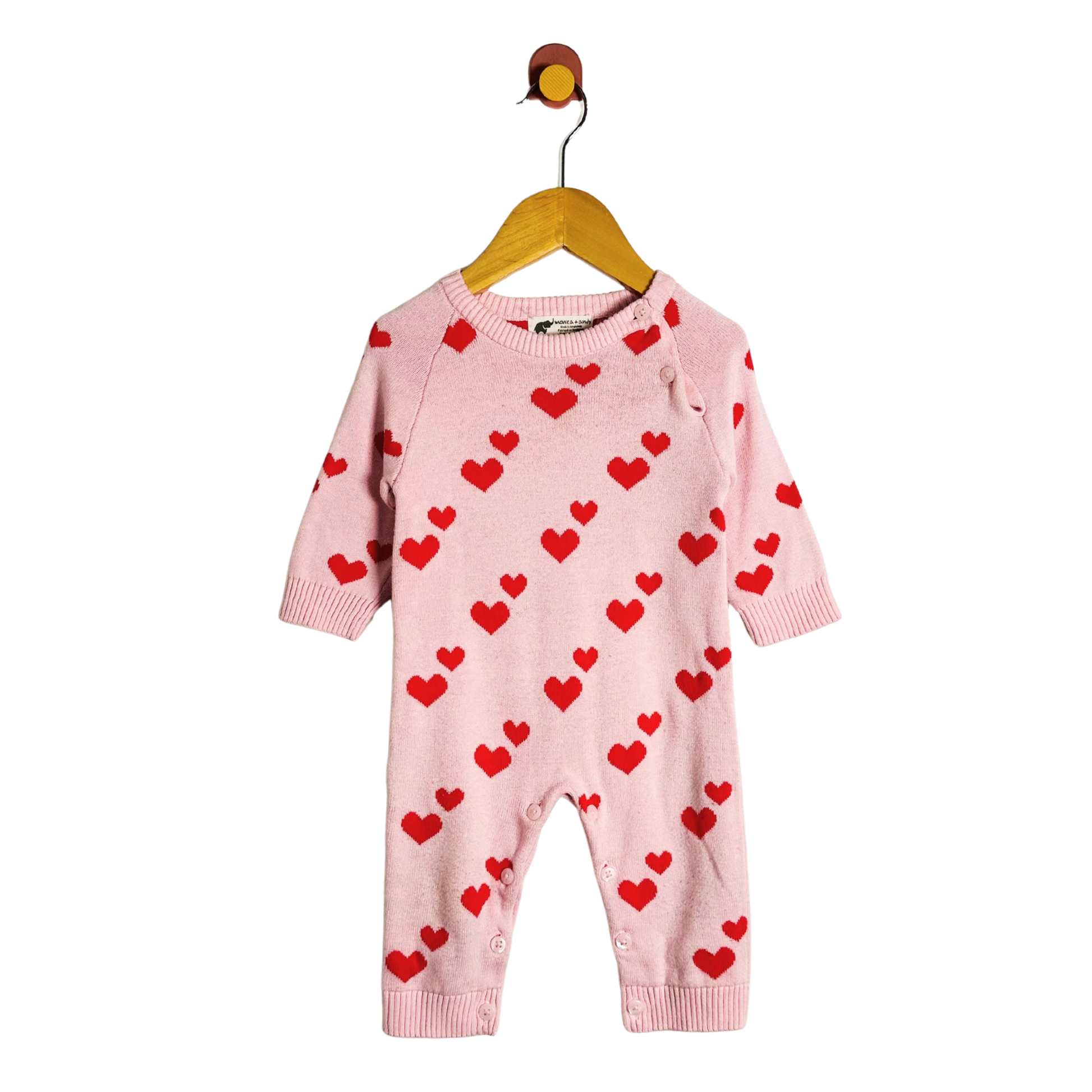 Pink baby romper with red heart patterns on a hanger against a white background