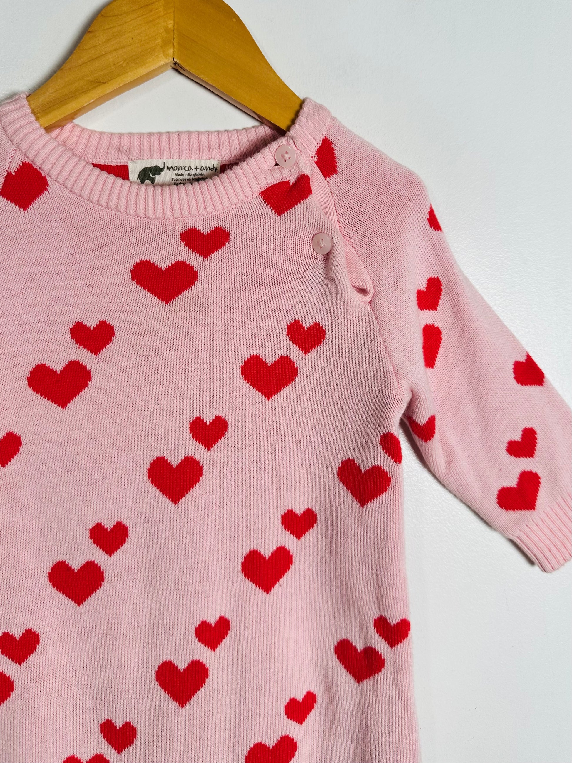 Pink sweater with red heart patterns on a white background
