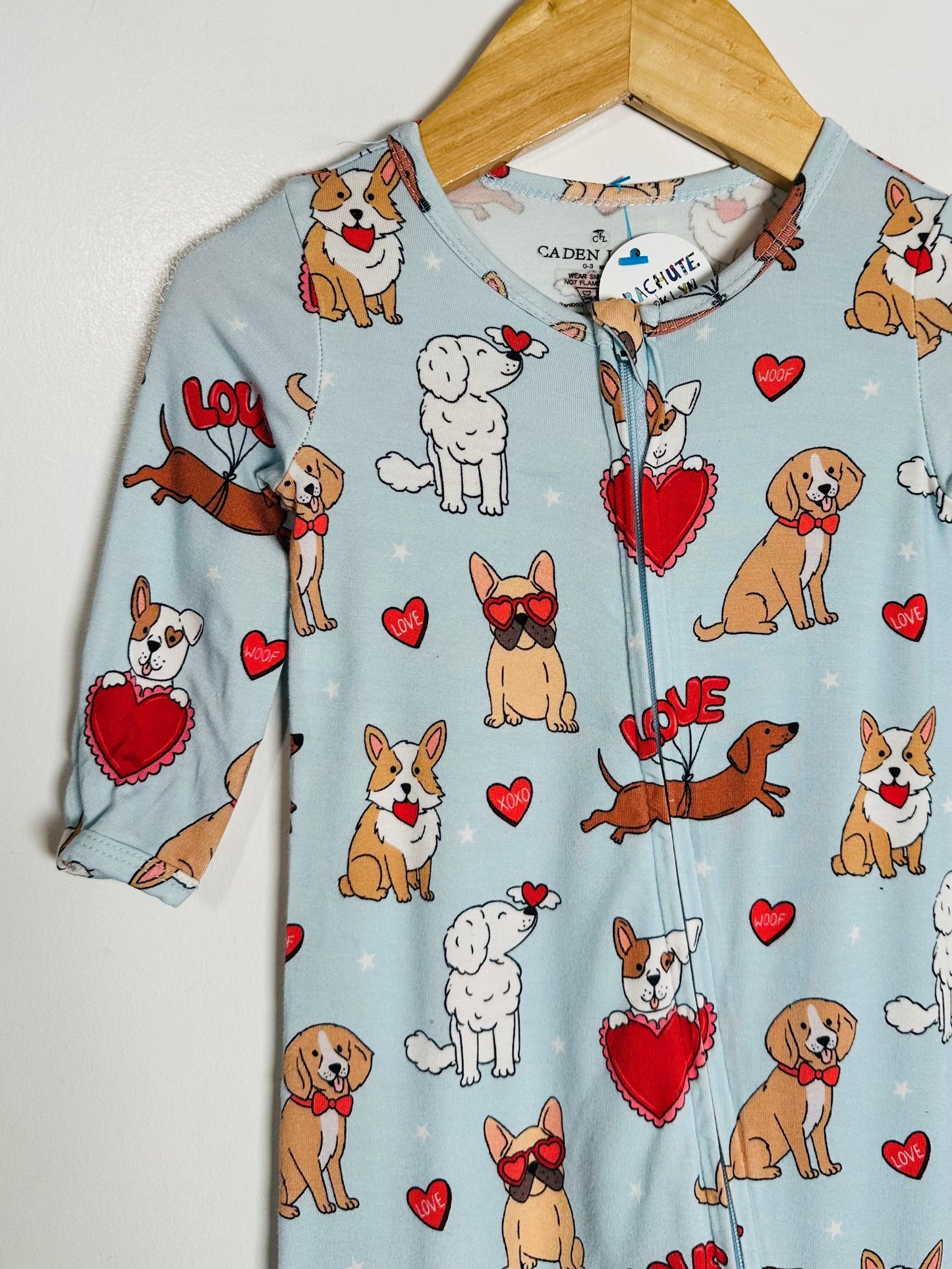 Children's onesie with dog pattern on a hanger against a white background